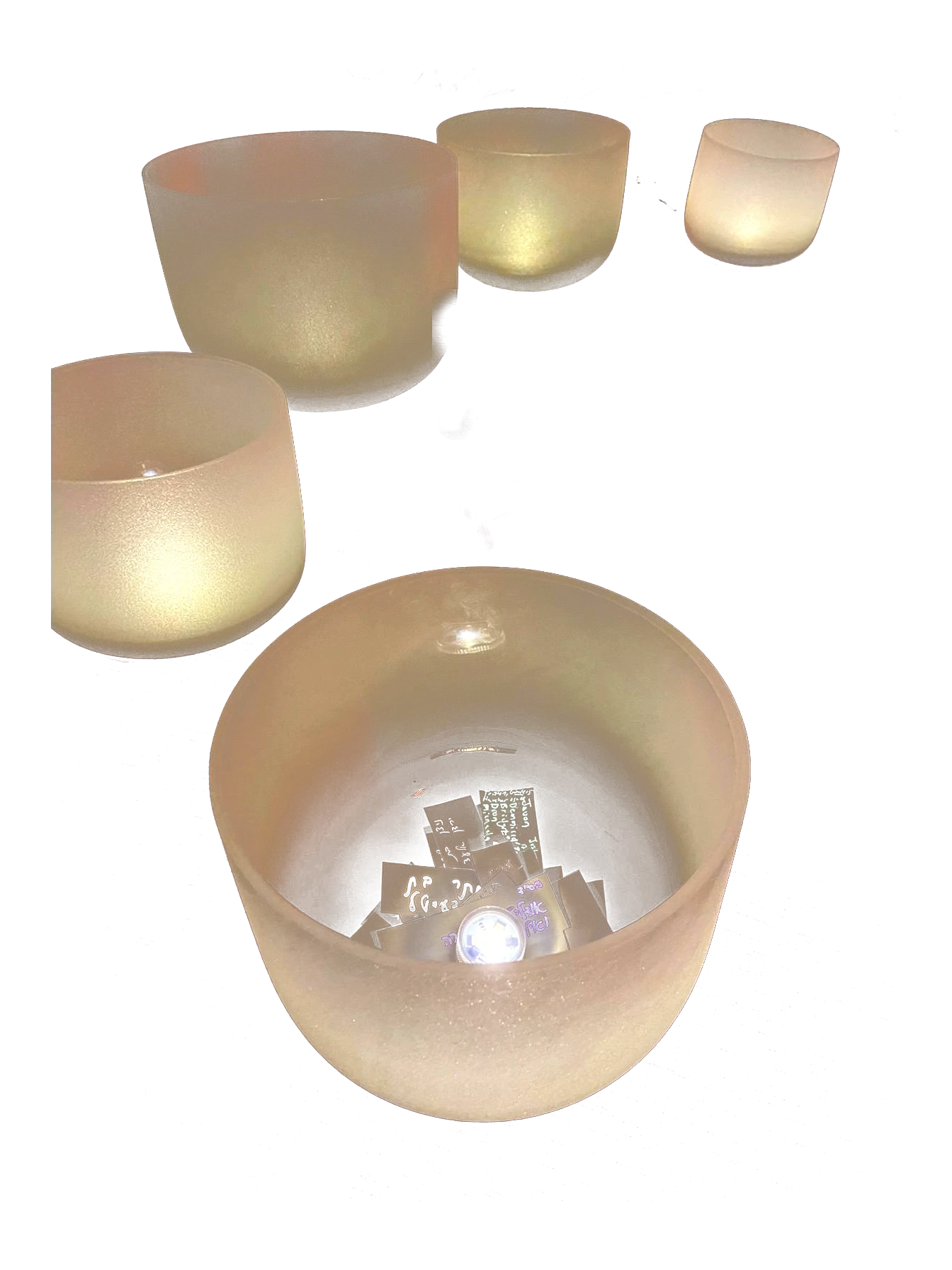 A group of crystal singing bowls glowing by candlelight