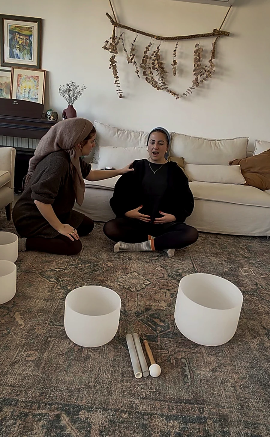 Tanya guiding a woman in vocalization beside crystal singing bowls