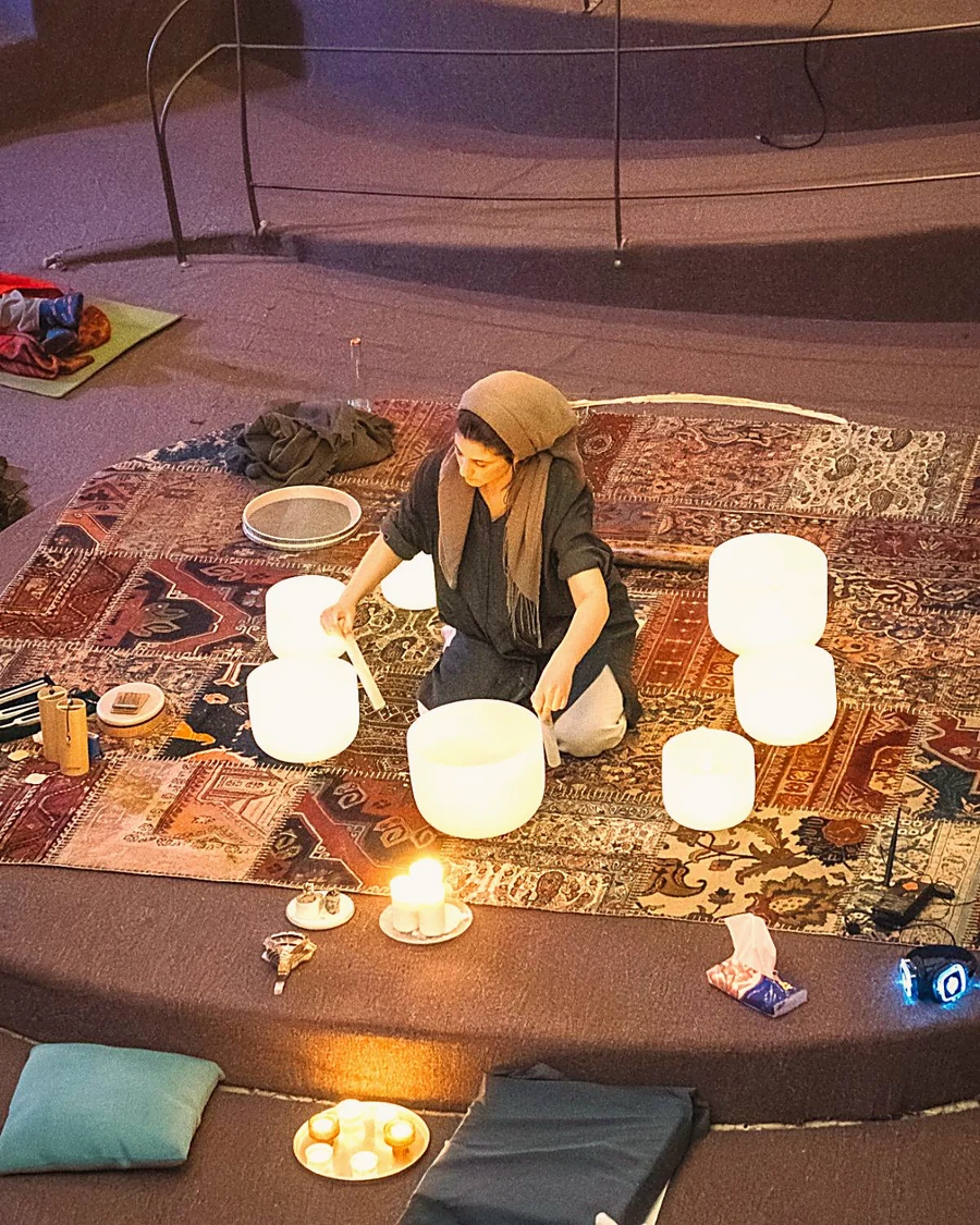 A candlelit sound bath with crystal singing bowls arranged on a rug
