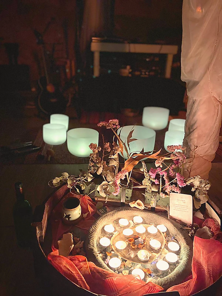 A candlelit altar with dried flowers and singing bowls glowing in the dark