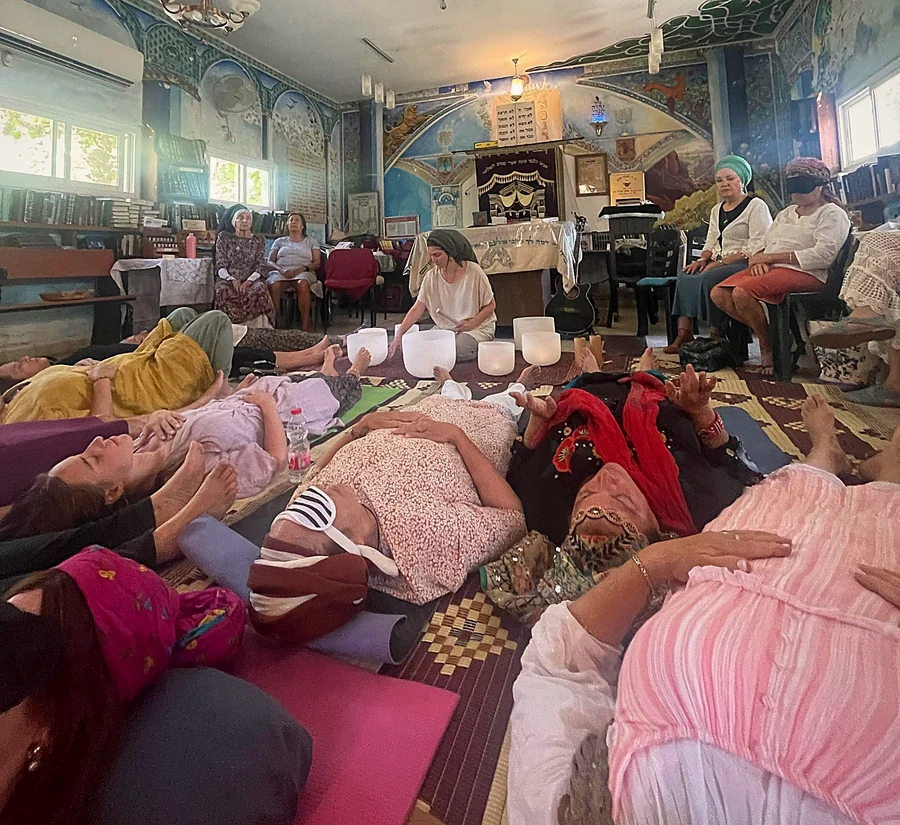 A circle of women resting in a sound bath in a painted synagogue
